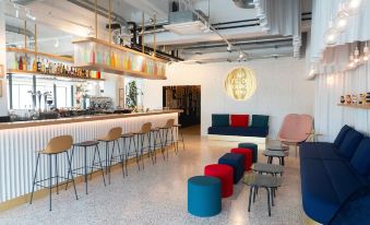 a modern bar area with various seating options , including couches and chairs , as well as a dining table at Ibis Styles Paris Romainville