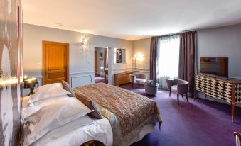 a large bedroom with a bed , nightstands , and chairs , as well as a window and dresser at Hotel Golf Chateau de Chailly