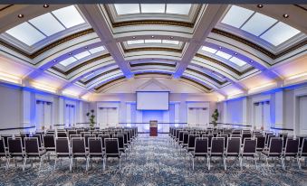 a large , well - lit conference room with rows of chairs arranged in front of a stage at Hilton Garden Inn Jackson Downtown