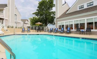 a large swimming pool is surrounded by chairs and an umbrella , with a building in the background at Sonesta ES Suites Cincinnati - Sharonville West