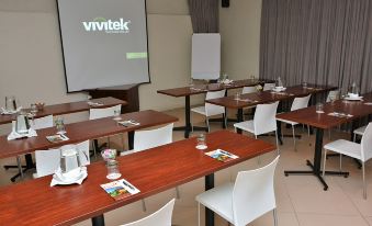 a conference room with several tables and chairs , a projector screen displaying the logo of vivitek , and a white napkin on each table at Balmoral Lodge
