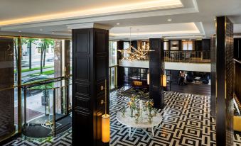 a luxurious hotel lobby with black and white checkered flooring , elegant furniture , and a large chandelier at Hilton Vienna Plaza