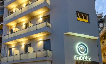 a tall hotel building with multiple stories and a green sign on the front , lit up at night at Marin Hotel