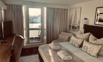 a large bed with a tray of folded towels on it is in a room with a window and artwork at Hotel Wroxham