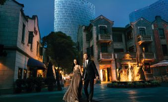 A couple poses in front of a building at night while another person photographs them at The Langham Shanghai Xintiandi