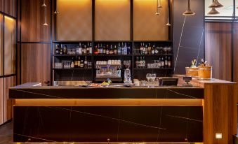 a modern bar with black granite countertops , wooden paneling , and a variety of liquor bottles on display at Doubletree by Hilton Brescia