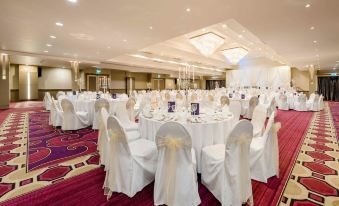 a large banquet hall with white tables and chairs , some of which are covered in white tablecloths at Hillgrove Hotel, Leisure & Spa