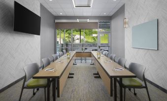 a long wooden table with chairs is set up in a conference room with large windows at SpringHill Suites Tuckahoe Westchester County