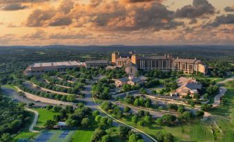 a grand hotel with a large courtyard , surrounded by lush greenery and mountains in the background at JW Marriott San Antonio Hill Country Resort & Spa