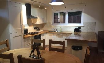 a kitchen with a wooden table and chairs , white cabinets , and a black bird statue on the counter at Shellow Lane Lodges