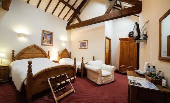 a cozy bedroom with wooden furniture , including a bed and dresser , along with a bed spread at Church Farm Lodge