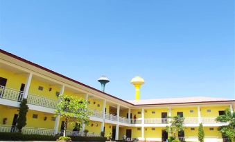 a yellow building with a balcony and two water towers is shown against a blue sky at Amonruk  Hotel 2