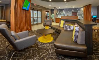 a modern hotel lobby with various seating options , including couches and chairs , as well as a tv at SpringHill Suites Centreville Chantilly