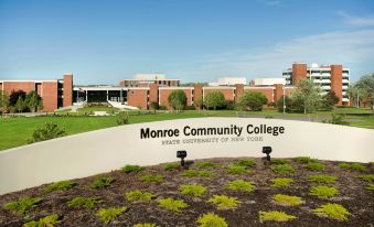 "a large white sign with the words "" monroe community college "" written on it , located in front of a building" at Courtyard Rochester Brighton