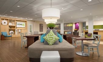 a large , open - concept living room with a couch and chairs , as well as a dining table in the background at Home2 Suites by HIlton Cartersville