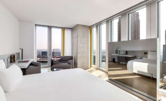 a modern bedroom with a white bed and a view of the city outside the window at Nhow Rotterdam