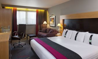a modern hotel room with a large bed , couch , and desk , along with various other furniture at Holiday Inn Aberdeen - West