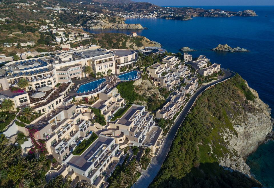 aerial view of a luxury resort on the coast , with multiple buildings and a body of water in the background at Athina Palace Resort & Spa