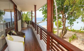 a wooden porch overlooking the ocean , with a view of palm trees and the water at Liberty Guesthouse Maldives