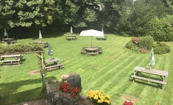 a lush green lawn with several picnic tables and umbrellas , creating a pleasant outdoor setting at Stanley Arms Hotel