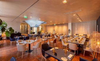 a large , modern restaurant with multiple dining tables and chairs arranged for guests to enjoy their meal at Hilton Vilamoura As Cascatas Golf Resort & Spa