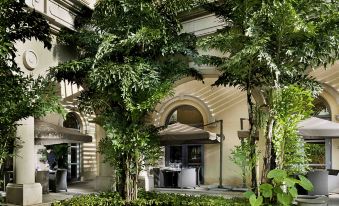 There is a courtyard with tables and chairs under an umbrella located next to the entrance of another building at Sofitel Macau at Sofitel Macau at Ponte 16