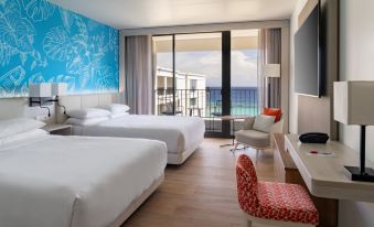 a hotel room with two beds , a window offering an ocean view , and a red chair at Curacao Marriott Beach Resort