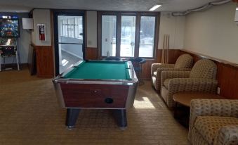 a billiards table is in the middle of a room with chairs and couches , overlooking a window at Pinestead Reef Resort