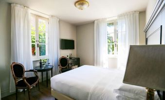 a bedroom with a large bed , two chairs , and a tv . the room is well - lit and appears to be inviting at Hotel Vannucci