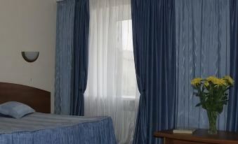 a hotel room with two beds , blue curtains , and a vase of flowers on a table at Avantage