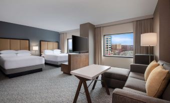 a hotel room with a bed , couch , and tv , as well as a window overlooking the city at Hyatt Regency Dulles