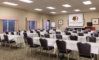 a large conference room filled with chairs arranged in rows and a projector screen on the wall at DoubleTree by Hilton Portland - Tigard
