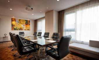a conference room with a glass table surrounded by black leather chairs and large windows at Lotte City Hotel Ulsan