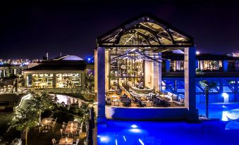 an outdoor dining area with a large glass roof , providing a view of the sky and city lights at night at Hotel Nikopolis