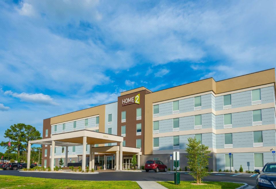 an exterior view of a large hotel building , possibly a hotel or inn , surrounded by grass and trees at Home2 Suites by Hilton Lake City