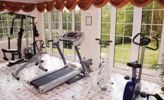 a well - equipped home gym with various exercise equipment , including a treadmill and stationary bike , in front of large windows at Glenspean Lodge Hotel