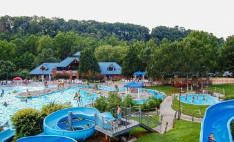 a large blue water park with multiple pools and slides , surrounded by trees and buildings at General Morgan Inn