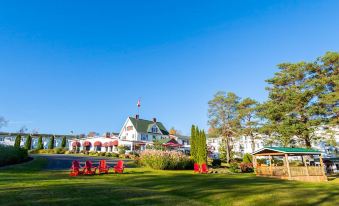 a large house with a red roof and white walls is surrounded by green grass and trees at Auberge Gisele's Inn