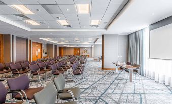a large conference room with rows of chairs arranged in a semicircle , providing seating for a group of people at Crowne Plaza Reading East