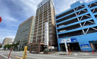 a city street with two tall buildings , one on the left and the other on the right , and a parking garage nearby at Toyoko Inn Oita Ekimae