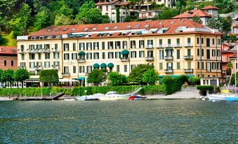 a beautiful waterfront area with buildings , boats , and trees , creating a picturesque scene on the water at Grand Hotel Menaggio