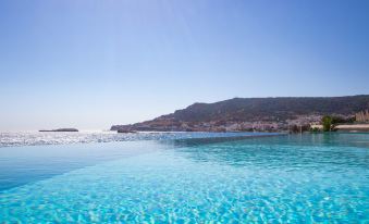 a large , clear blue swimming pool with clear water and clear sky in the background at Konstantinos Palace