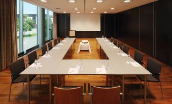 a large conference room with a long table , chairs , and various items on the table at Four Points by Sheraton Panoramahaus Dornbirn