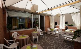 an outdoor dining area with tables , chairs , and umbrellas under a covered patio , creating a cozy atmosphere at Art Hotel
