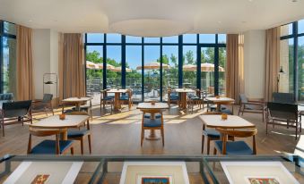 a restaurant with wooden tables and chairs , large windows , and an outdoor view of the outdoors at H10 Imperial Tarraco