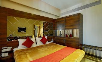 a luxurious hotel room with a large bed , red and gold bedding , and a mirror on the wall at Hotel Apaar