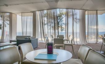 a dining area with a table and chairs , as well as a couch in the background at Vitality Hotel Punta