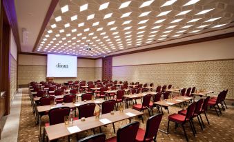 a conference room with rows of chairs arranged in a semicircle , and a projector screen on the wall at Divan Istanbul