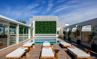 a large swimming pool with white lounge chairs and a green wall in the background at Athens Marriott Hotel