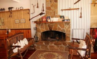 a cozy living room with a stone fireplace , wooden furniture , and a rug on the floor at Mountain View Country Inn